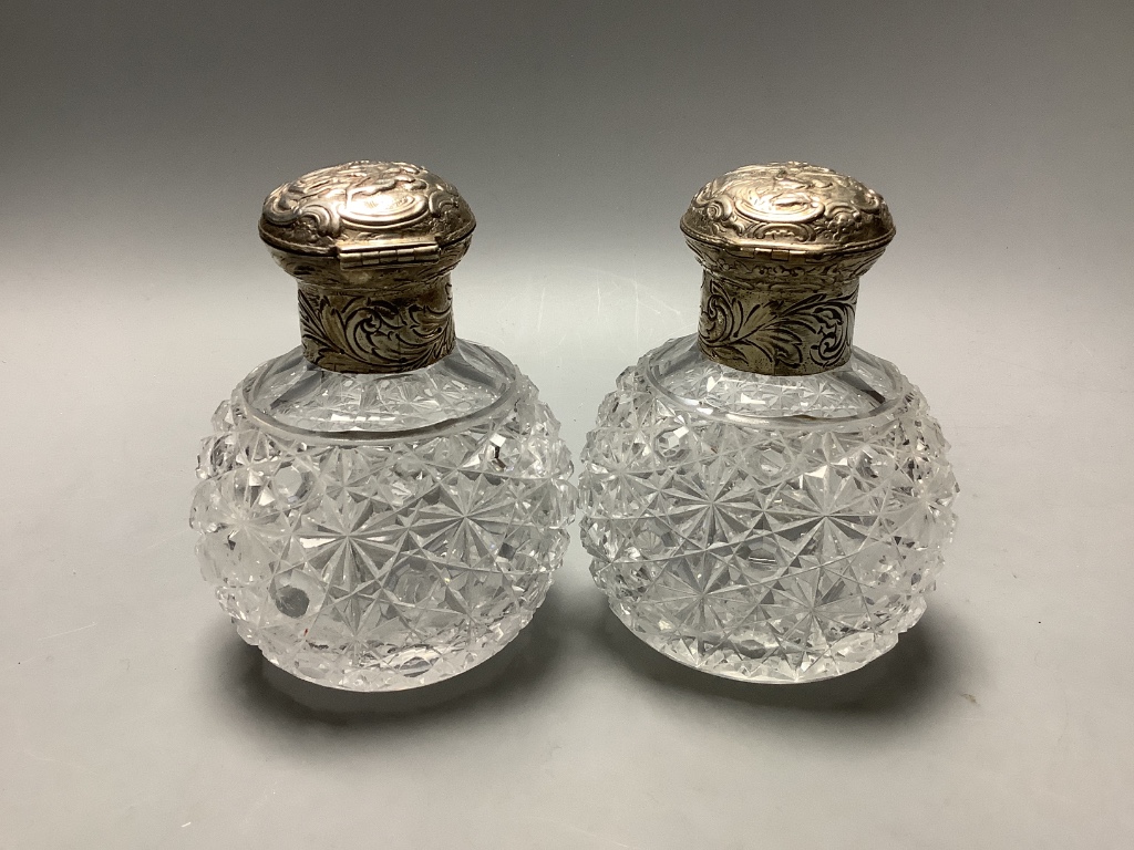 A pair of late Victorian silver mounted cut glass scent bottles, London, 1887, height 13.1 cm and a silver and tortoiseshell powder jar.